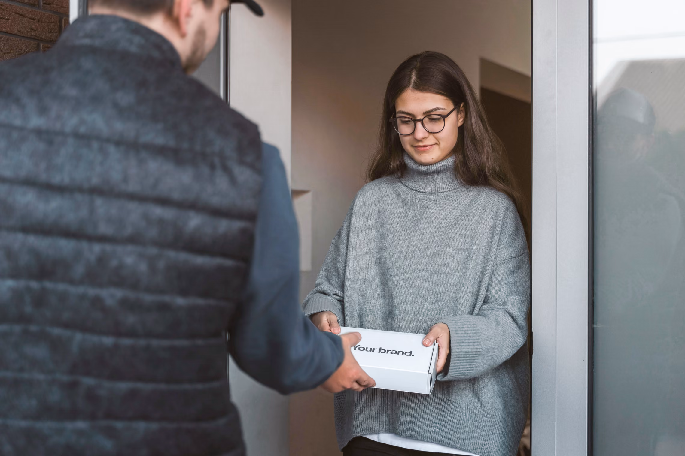 A courier handing a branded kit box to someone at their front door